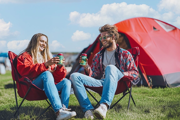 Doi prieteni stau pe șezlonguri în campingul de la festival.