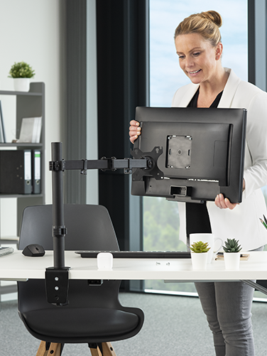 A woman attaches a PC monitor to the Hama monitor mount at her workplace